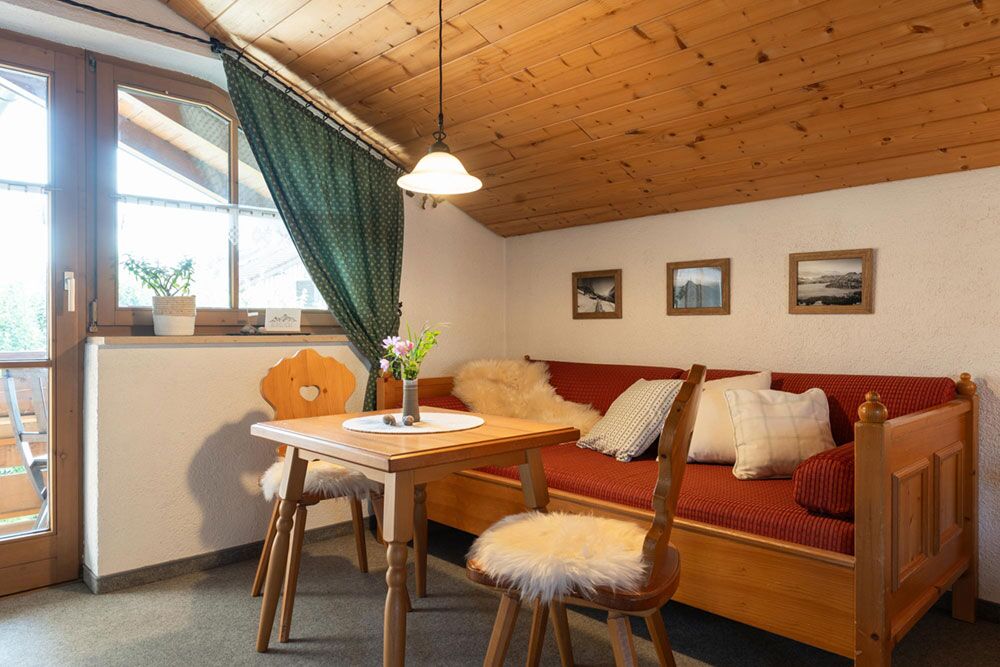 Helle Essecke mit Holztisch und Fensterblick in der Ferienwohnung Martin im Allgäu
